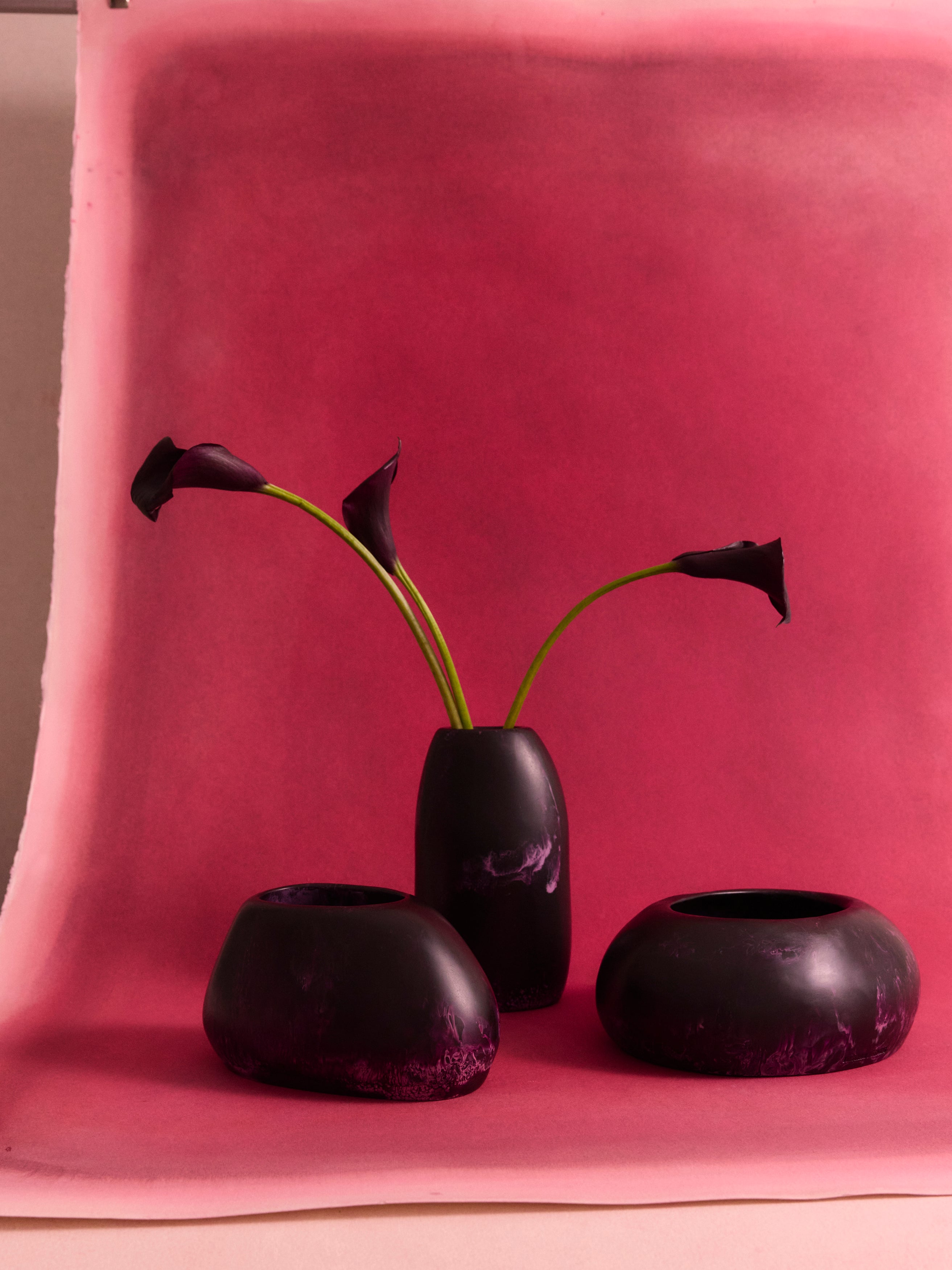 Deep purple vases with calla lilies on a pink background