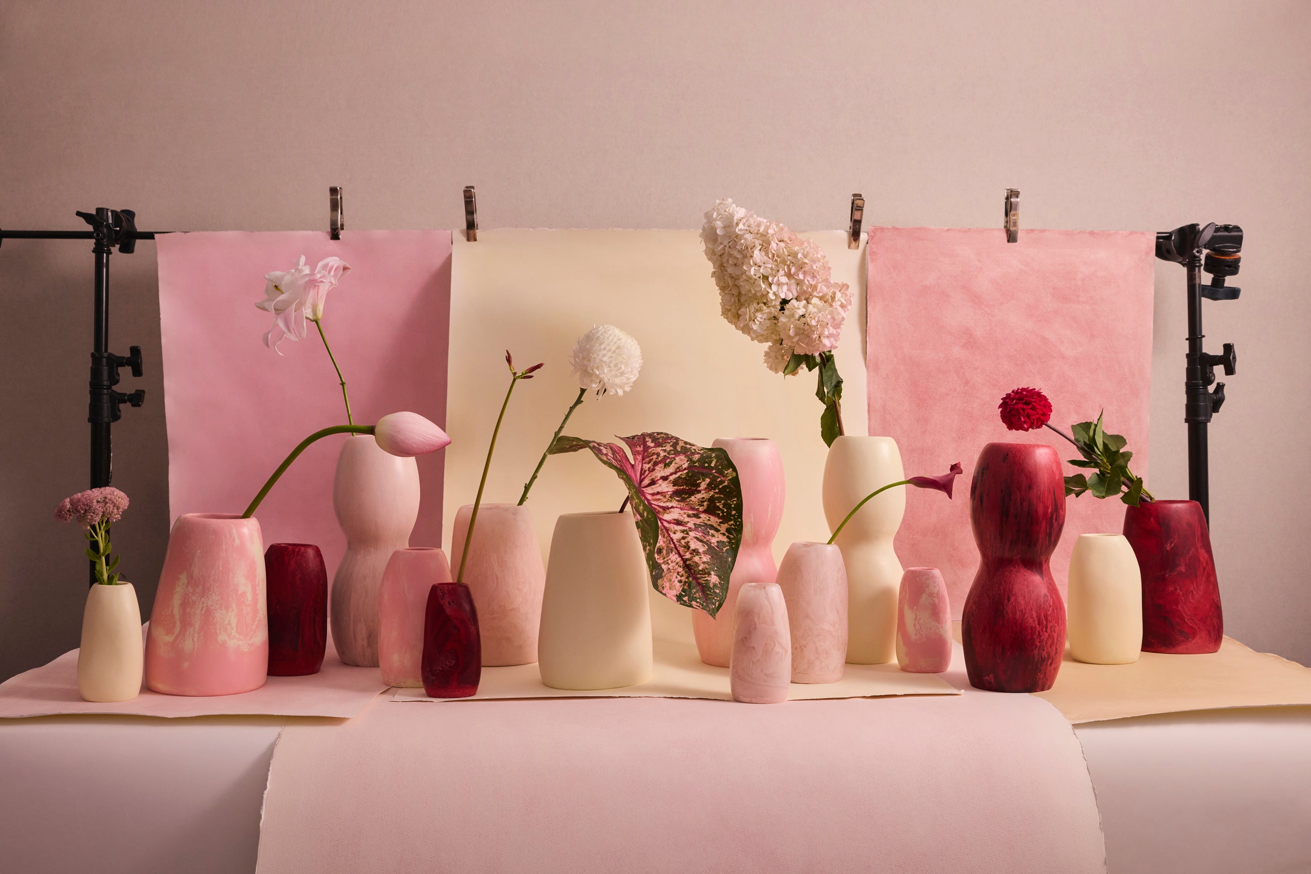 A collection of pink and cream resin vases with a variety of different floral stems
