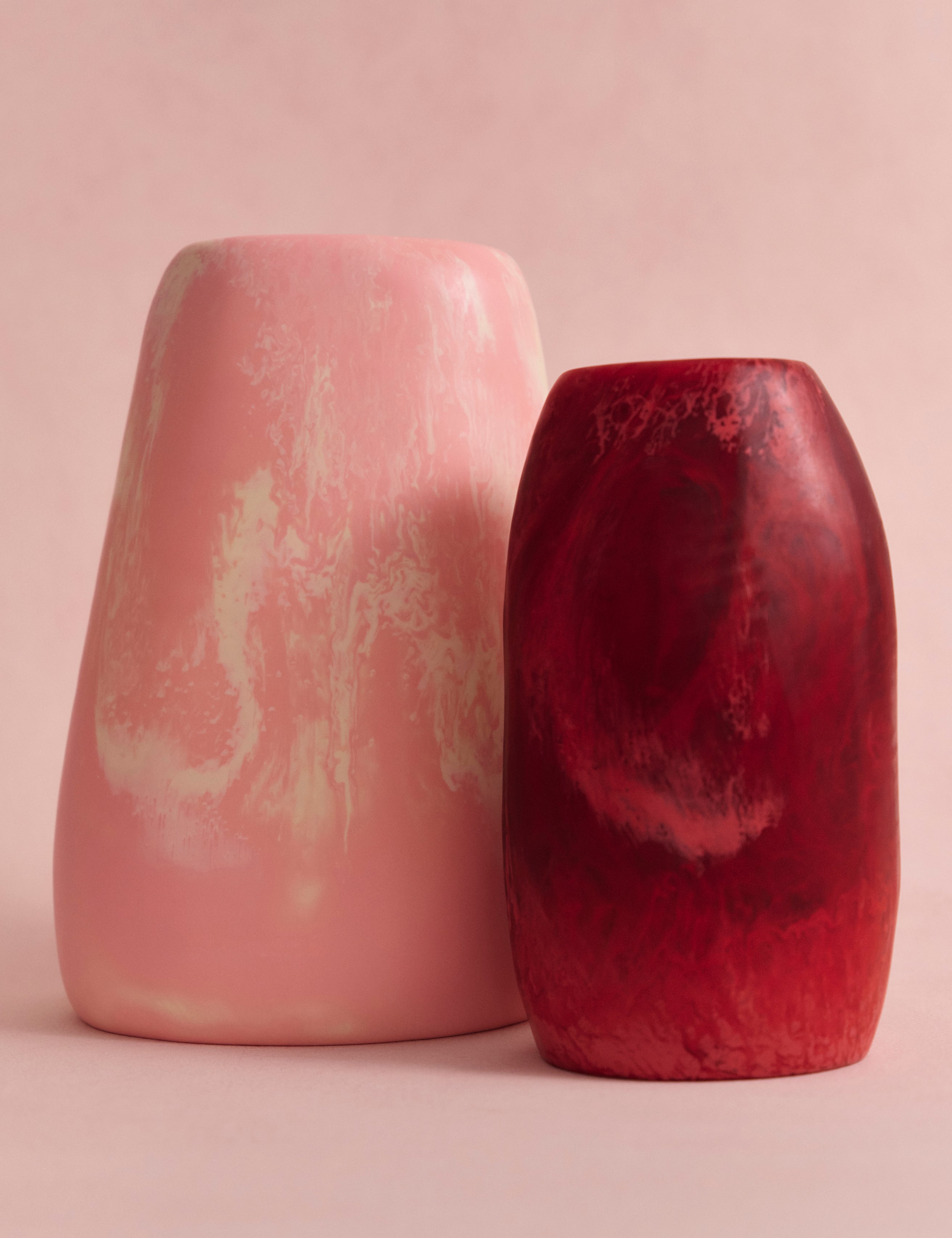 Two resin vases in pink and cream marbling, and deep pink on a light pink backdrop