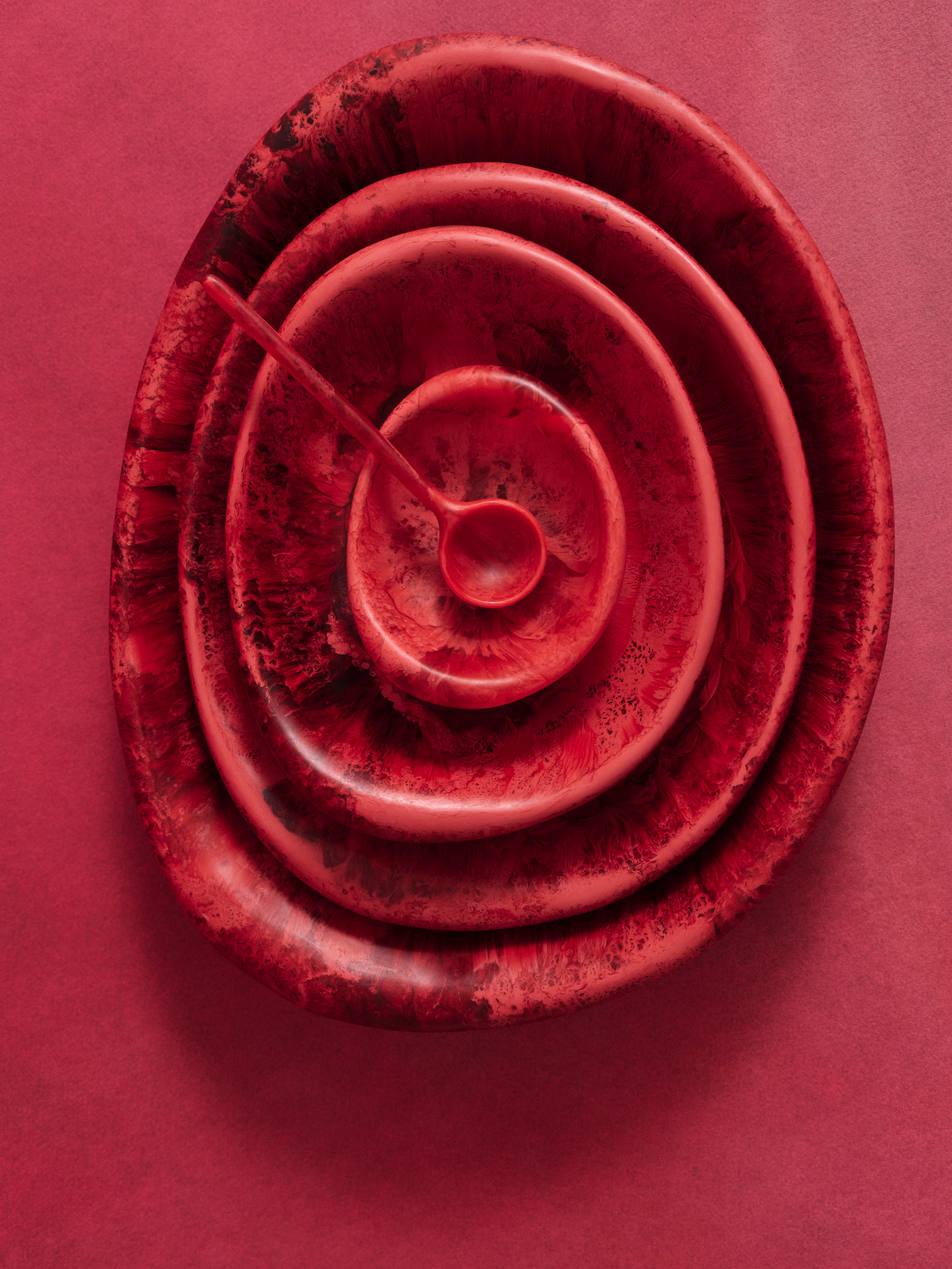 Stack of deep pink serving bowls on a pink backdrop with a deep pink spoon atop