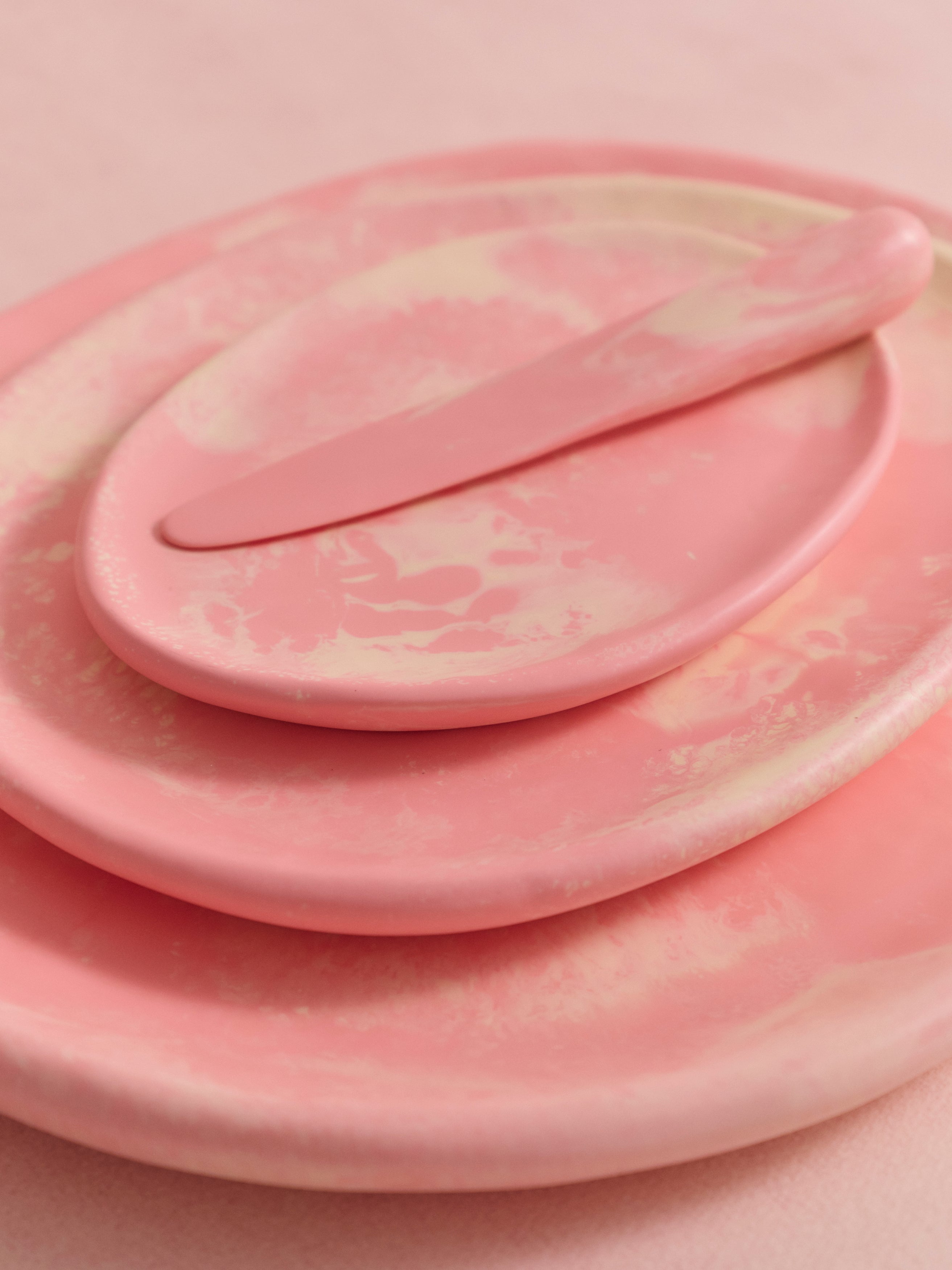 Stack of pink resin serving plates with a pink resin cheese knife atop