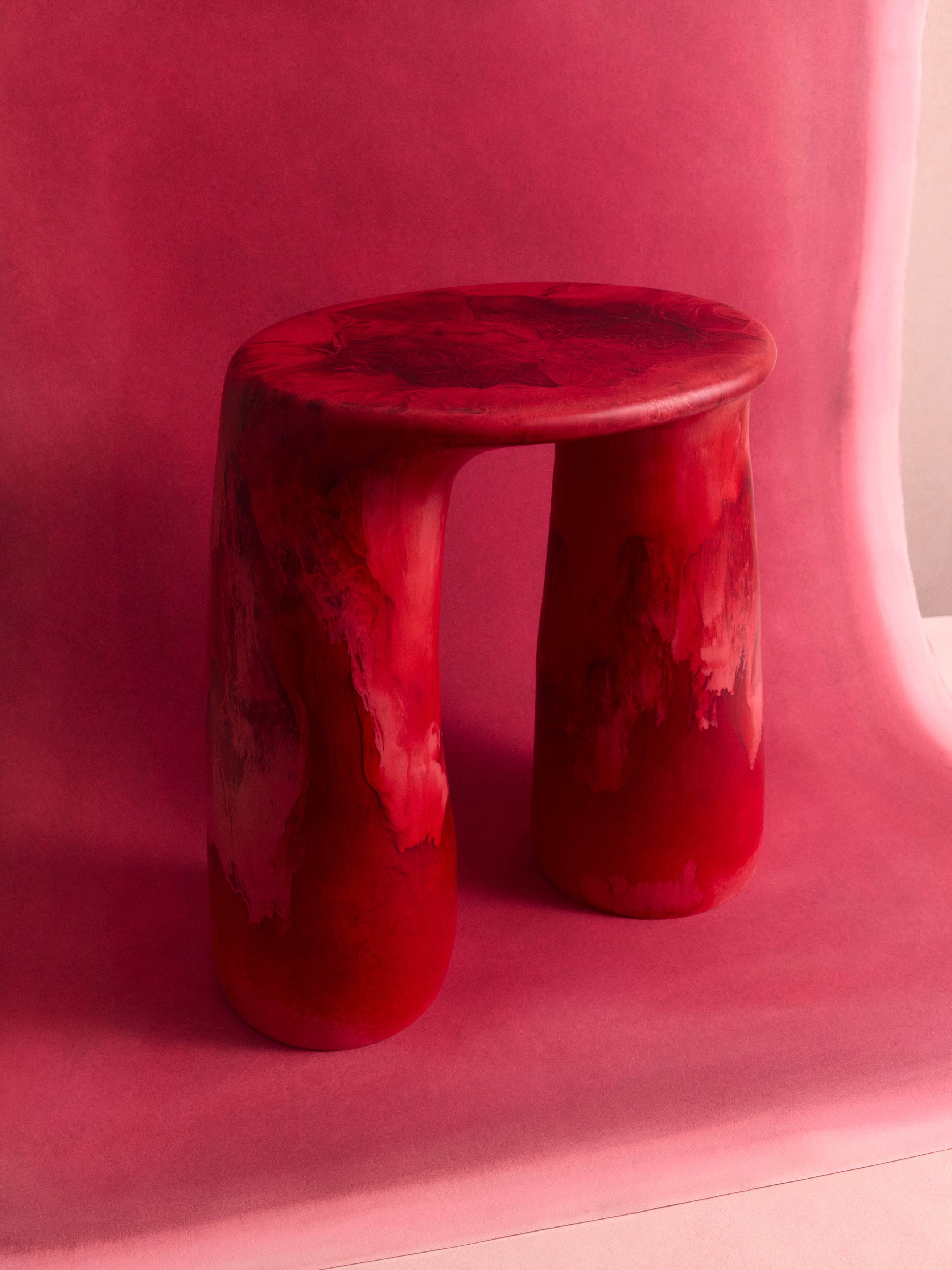 Deep red two legged table on a pink backdrop