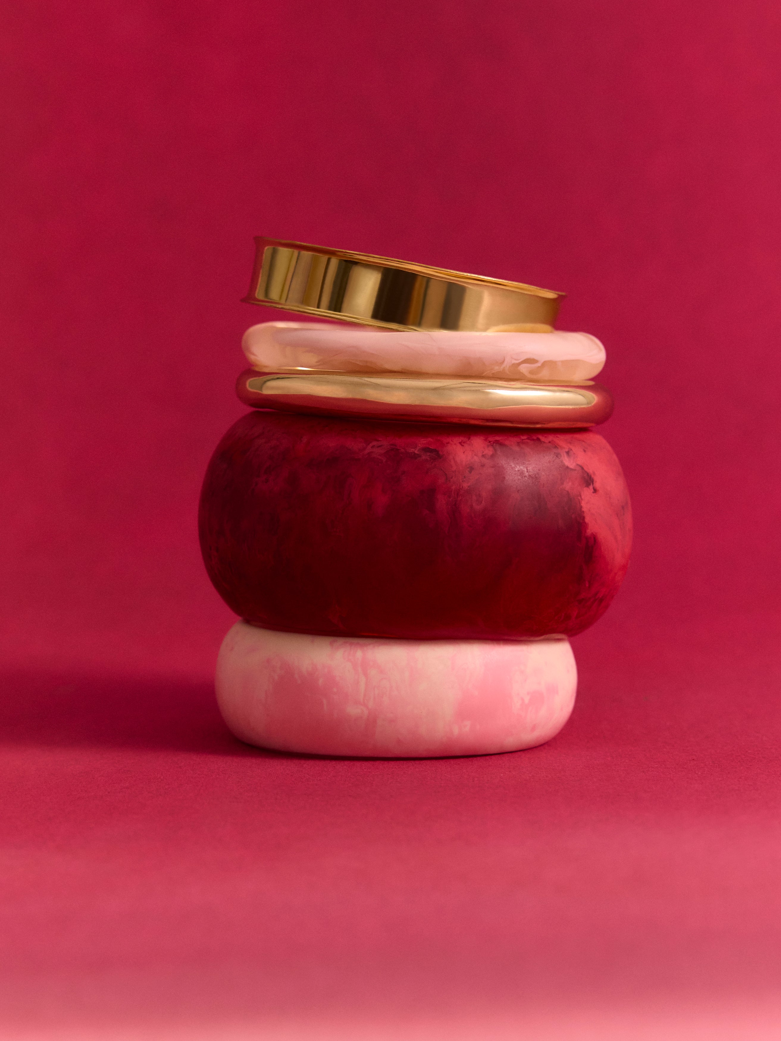 Stack of pink and brass bangles on a pink backdrop