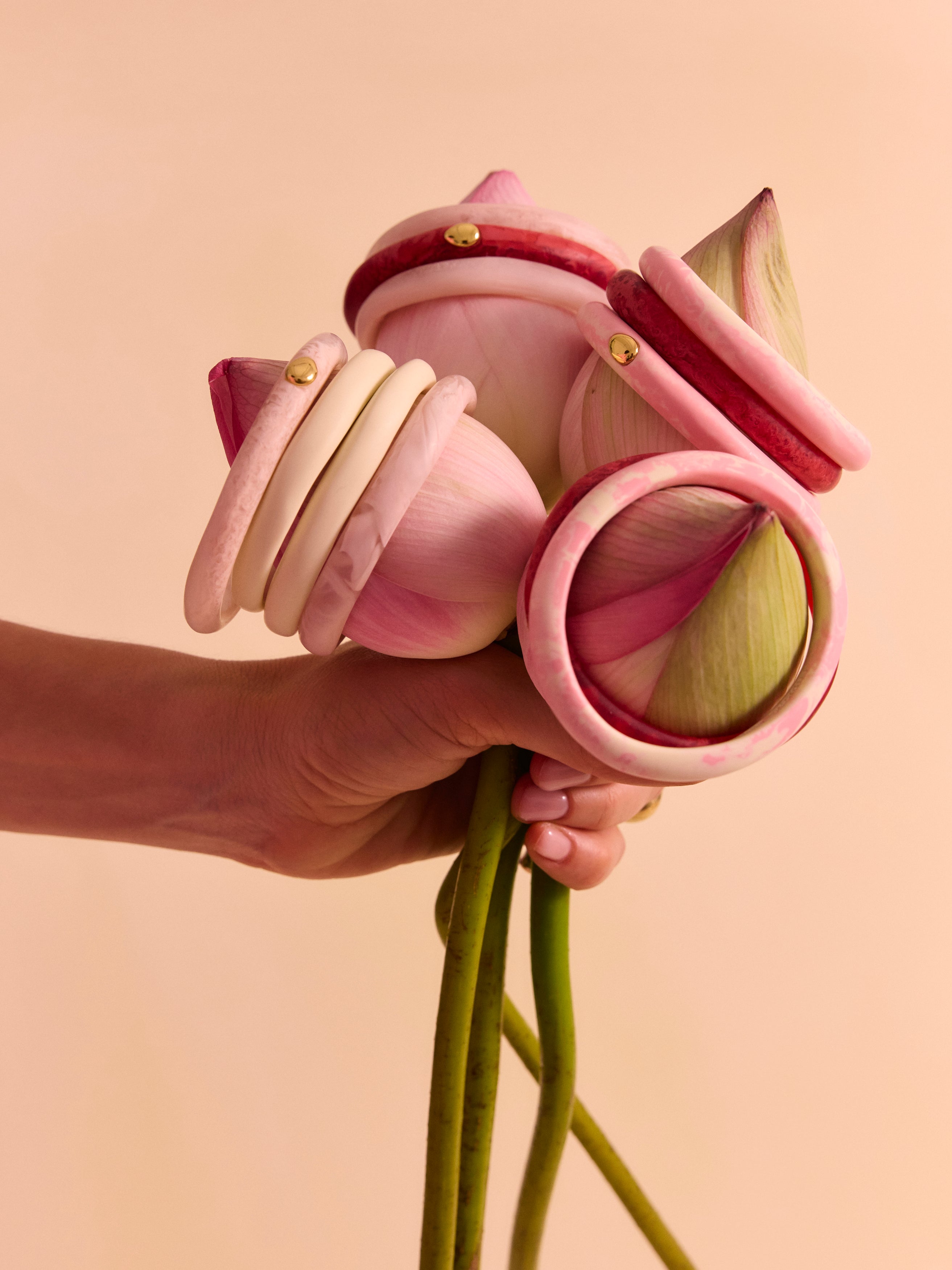 Hand holding a bunch of flowers with pink and cream bangles