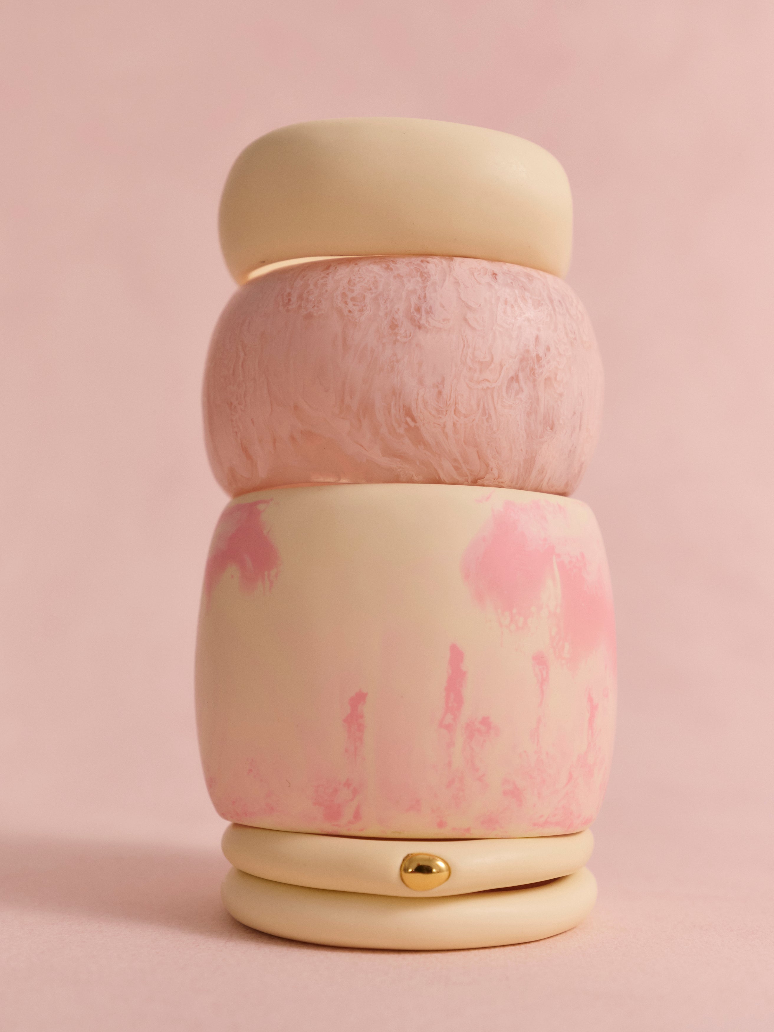 Stack of pink and cream bangles on a light pink backdrop