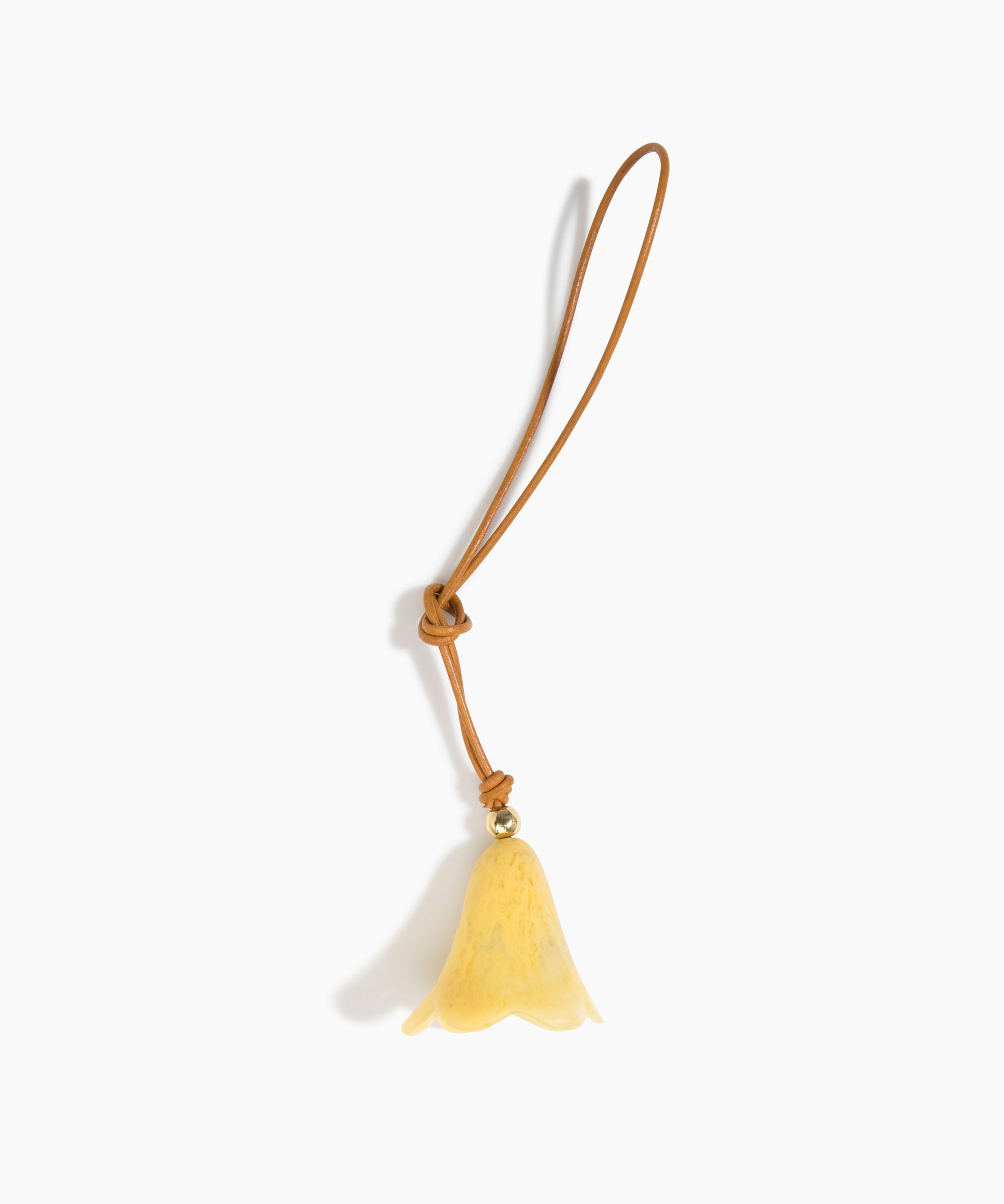 Dinosaur Designs Flower Bag Charm in Pollen colour with Brass bead — handcrafted marbled yellow resin bell-shaped flower bag charm with tan leather hanging loop and brass bead