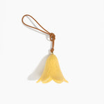 Dinosaur Designs Flower Decoration in Pollen colour with Brass bead — handcrafted marbled yellow resin bell-shaped flower ornament with tan leather hanging loop and brass bead