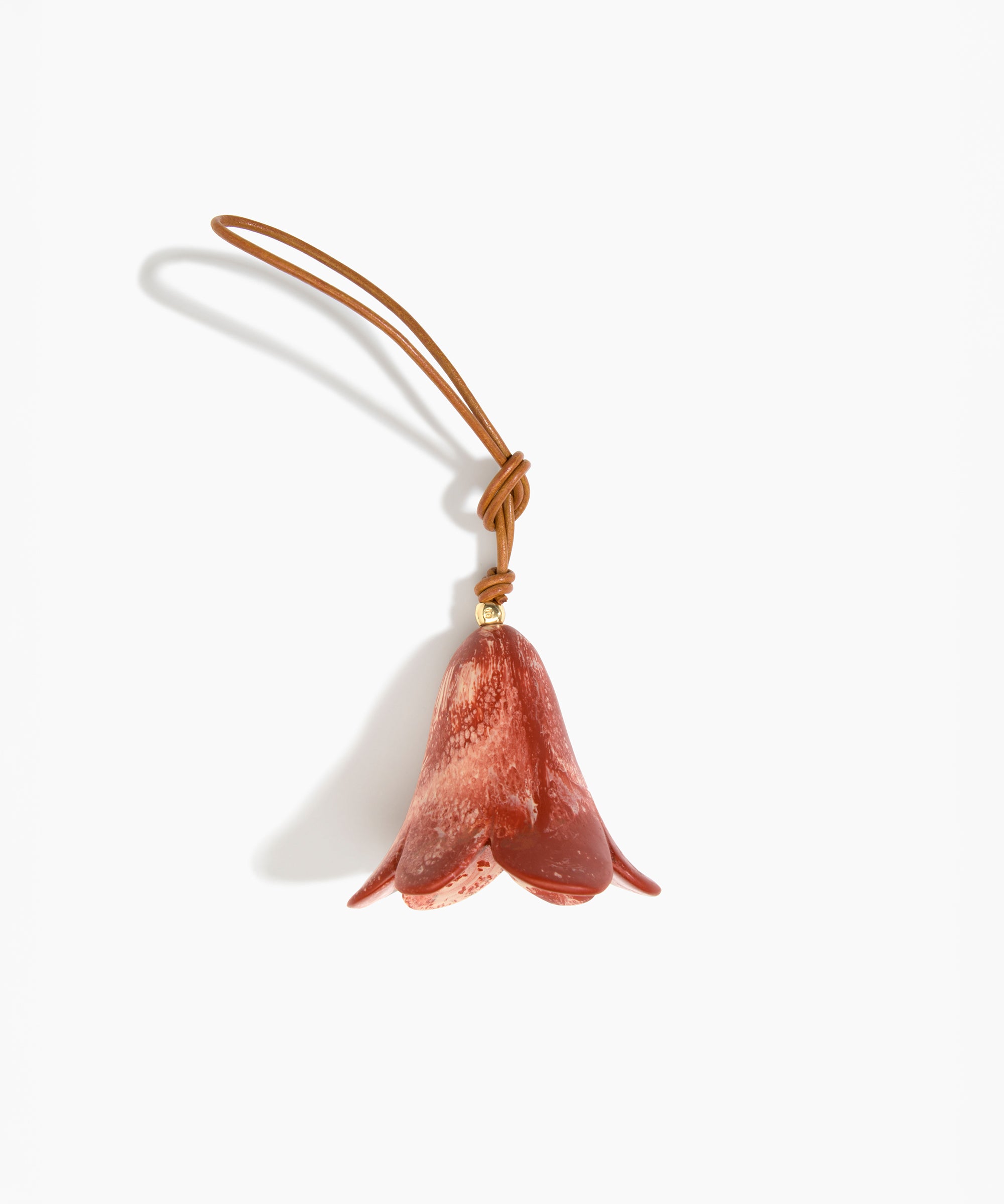 Dinosaur Designs Flower Decoration in Rust colour with Brass bead — handcrafted marbled terracotta red and cream resin bell-shaped flower ornament with tan leather hanging loop and brass bead