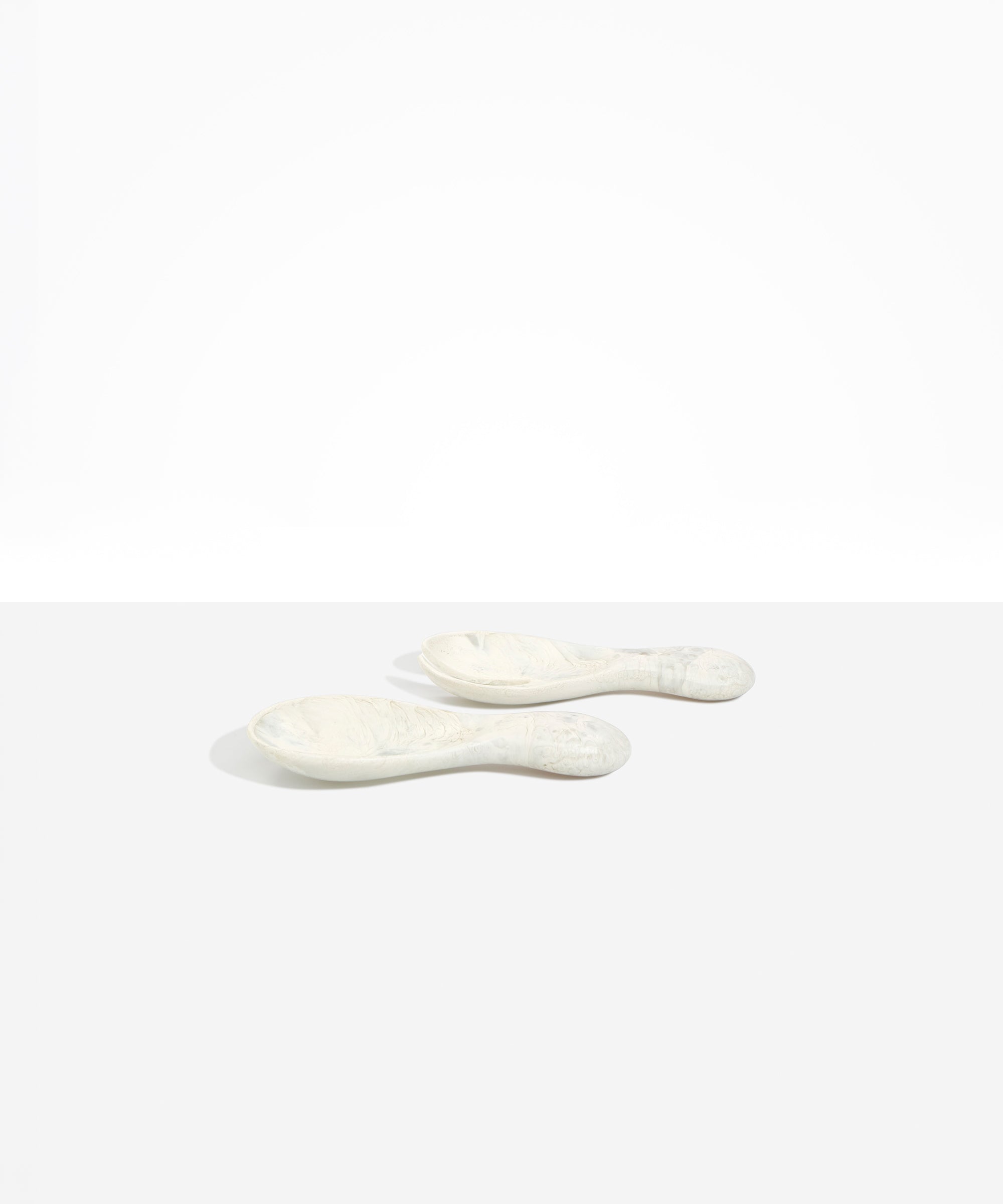 Dinosaur Designs Rock Servers in Chalk Swirl — handcrafted marbled off-white resin salad server set with rounded bulb handles, fork and spoon.