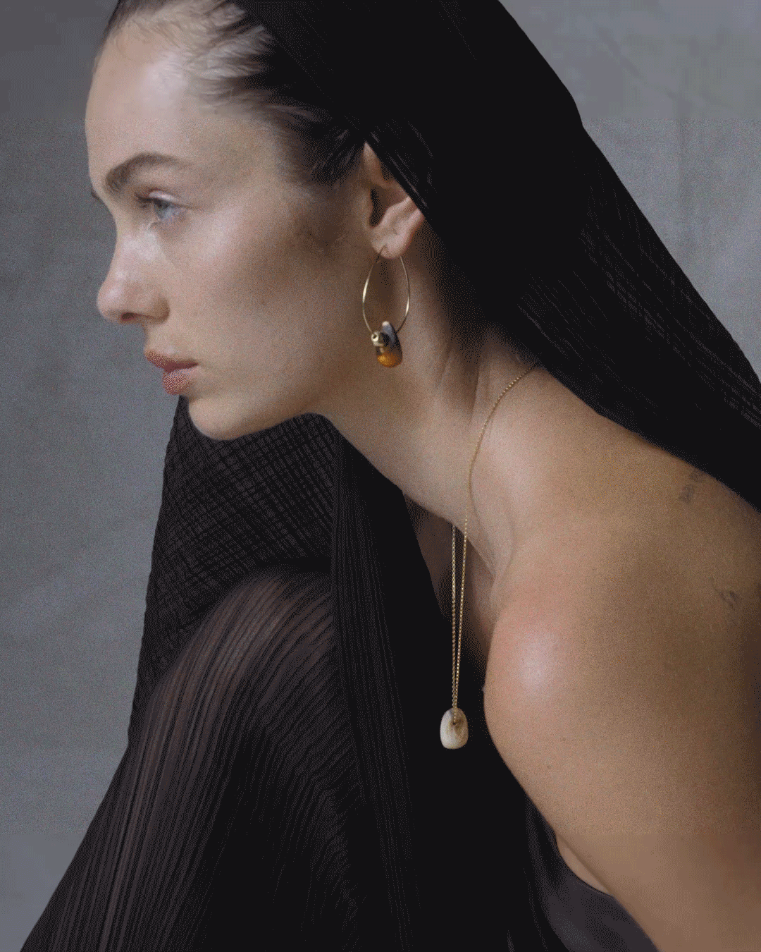 Model wearing neutral gold hoop earrings and neutral necklace on gold chain